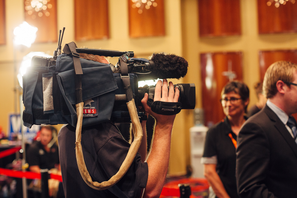 A Southern Cross TV news cameraman films a presenter delivering the news